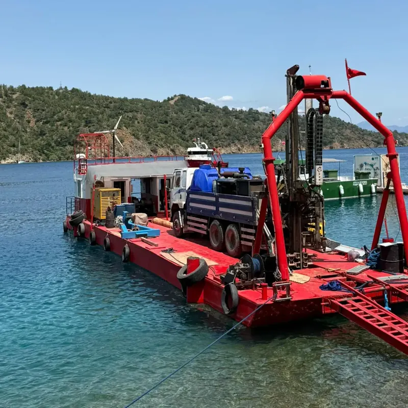 Koyda demirli yüzer platform üzerinde kamyona monte sondaj makinesi ile deniz sondajı