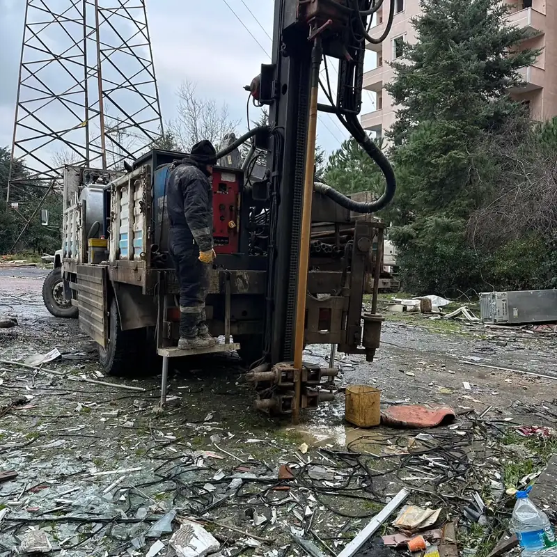 Mevcut bina çevresinde çalışan kamyona monte sondaj makinesi ve operatör